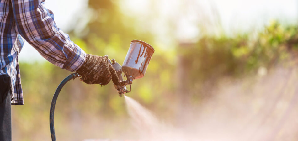 Construction,worker,spraying,paint,to,steel,pipe,to,prevent,the